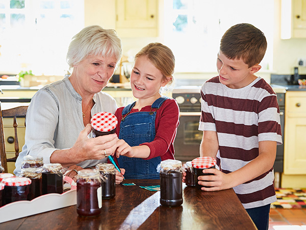 Grandkids helping grandmother with jars of jam